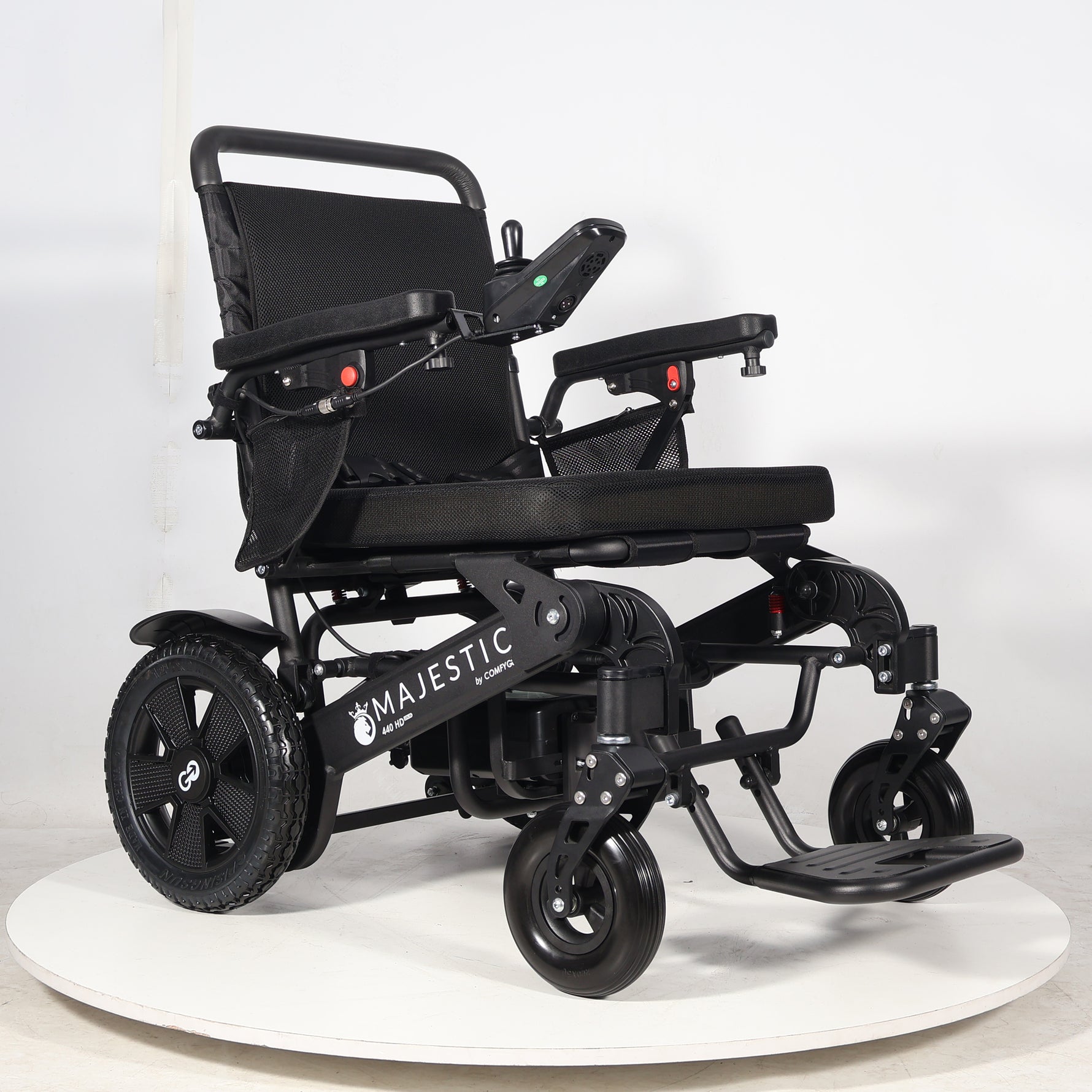 Black electric wheelchair on a white platform with a white background